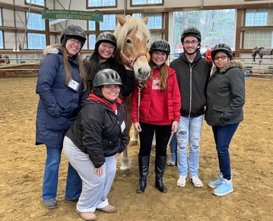 Girls Inc Greater Lowell staff stands with a horse after a riding field trip.
